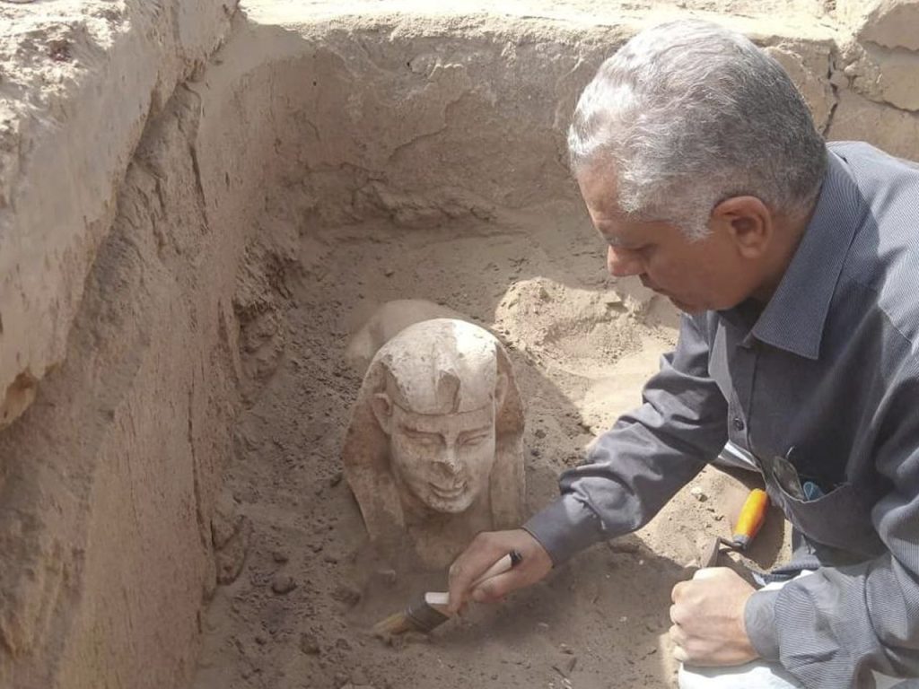 An archaeologist brushes away loose sand after the head of the sphinx had emerged. Photo: Ministry of Tourism & Antiquities