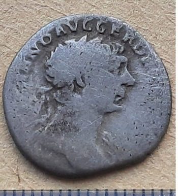 A silver denarius showing the face of Roman emperor Trajan.