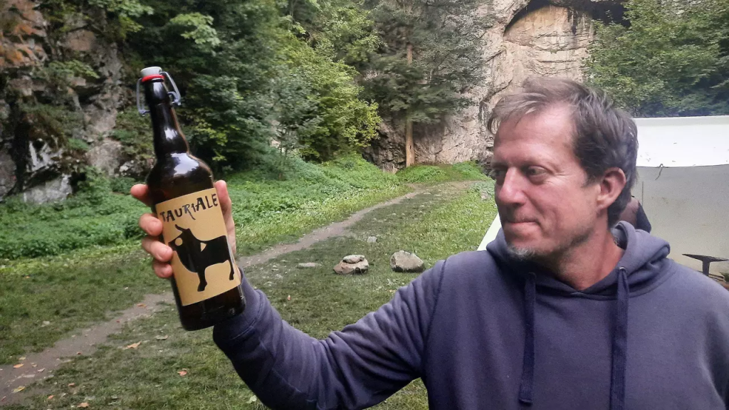 Archaeologist Martin Golec shows the first Celtic beer in the Czech Republic, newly produced based on pollen samples taken from the burial site in the Býčí skála cave in the background.