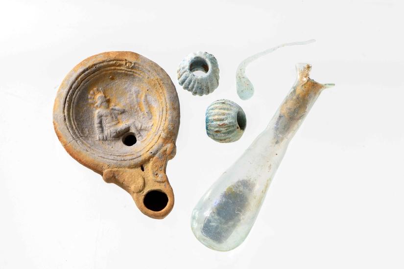 Roman lamp, glass vial, and beads from a cremation burial. Image: ©MOLA