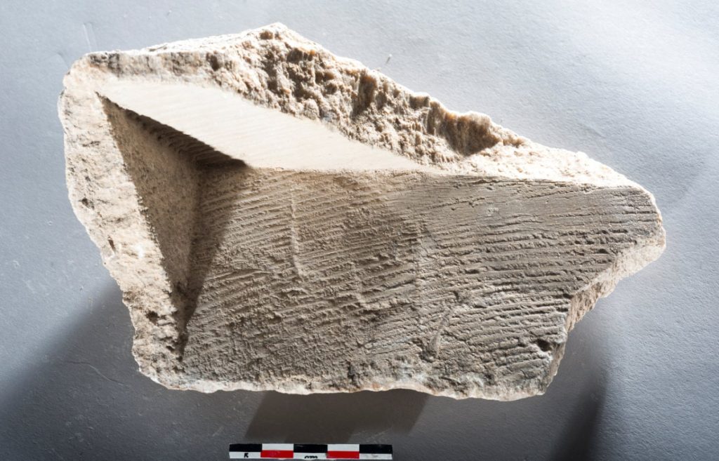 Cross-section of a carbonate fragment from the Barbegal mills. The deposit has formed on the wood of the mill wheels and shows imprints of wood and traces of woodworking. Photo: Philippe Leveau