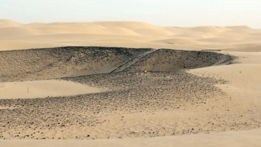 A view over the central sector of Saruq al-Hadid, showing the dark surface layer of copper slag that distinguishes the site from the surrounding desert landscape. Photo: Weeks et al., 2019