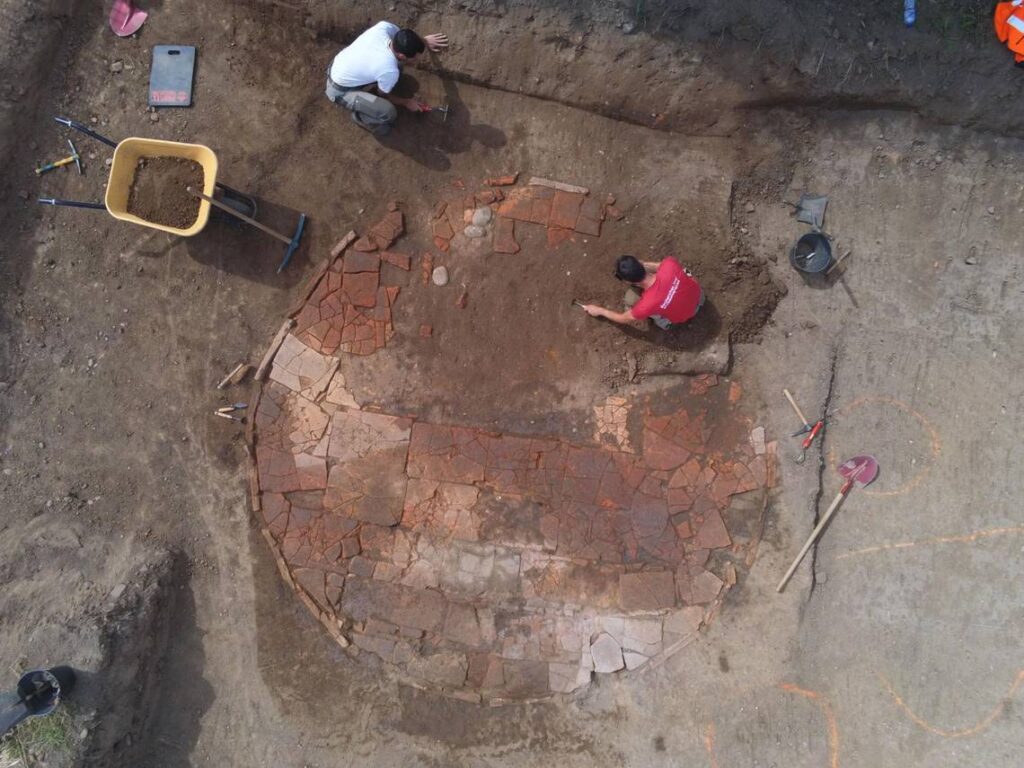 Archaeologists excavate an ancient tile wash basin. Photo: Brice Chevaux/Inrap