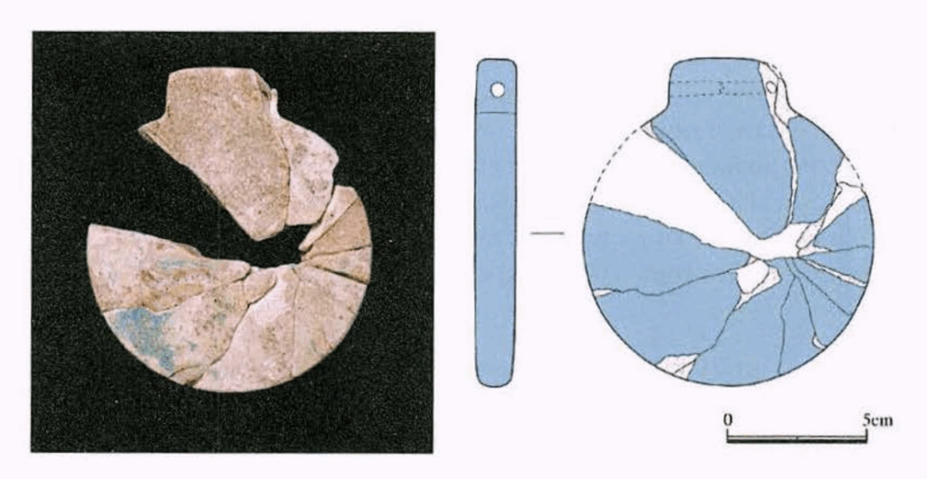 Glass pendant from Room R14. The disk-shaped design bears stylistic parallels to votive offerings associated with the Mesopotamian goddess Ishtar. Credit: Japanese Institute of Anatolian Archaeology.
