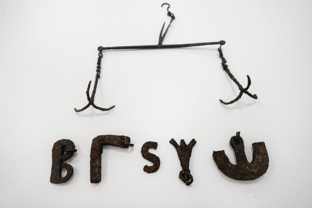 A set of balance scales and five iron weights shaped like letters, believed to be 1,600 years old, were uncovered during archaeological excavations at Uzuncaburç. Credit: AA