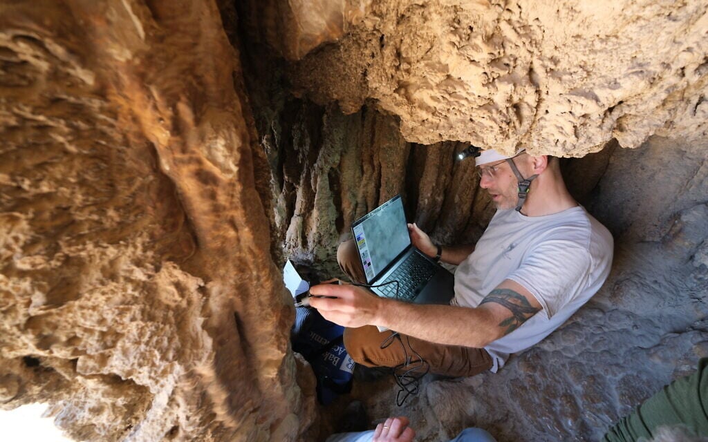 Dr. Asaf Gayer from the Department of Land of Israel Studies and Archaeology, Ariel University, examines a cave near the Ein Gedi National Park in the Dead Sea region, featuring an ancient Aramaic inscription, possibly dated to the Bar Kochba Revolt, that was first revealed to the public in August 2025. Image credit: Asaf Gayer