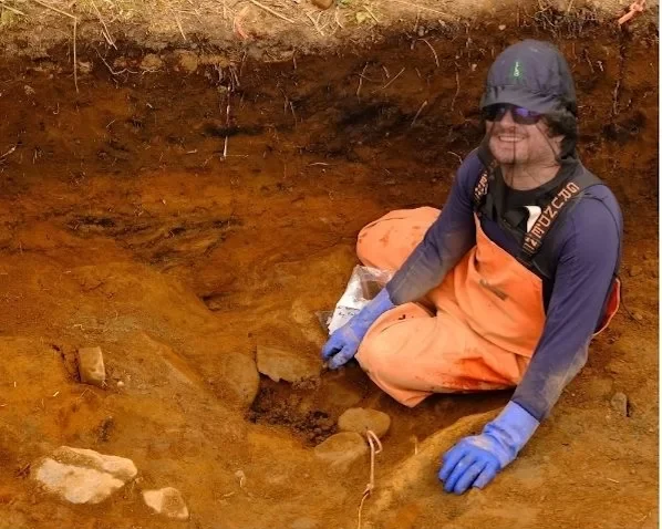 Trevor Lamb excavates a small cobble hearth at the Alagnaruartuliq site. Charcoal from this feature dated to about 7800 years ago. Credit: Alutiiq Museum 
