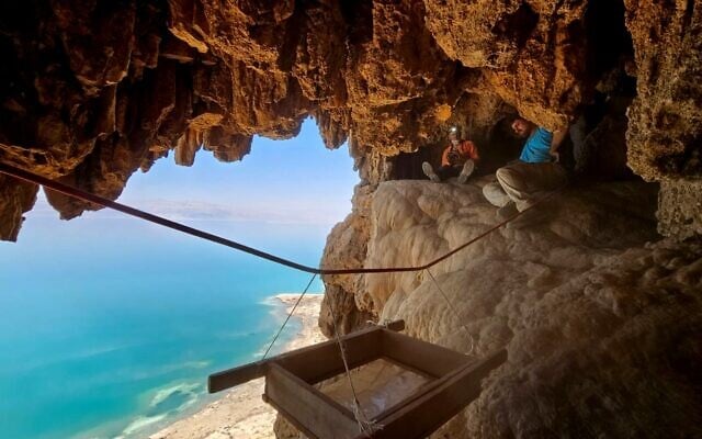 Archaeologists at work excavating the cave where an Aramaic inscription and four Roman swords were discovered in the Judean Desert, with a view of the Dead Sea. Credit: Oriya Amichai/IAA