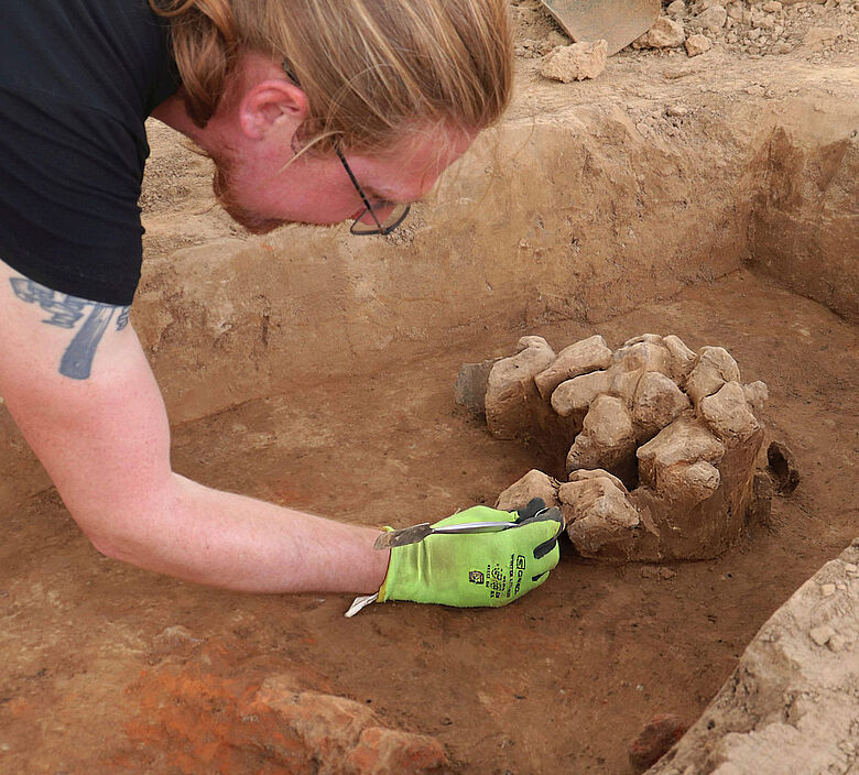 In one of the Iron Age pits, an unusual concentration of stones was uncovered and is being carefully excavated. Credit: LQ Archaeology / C. Bariszlovich.