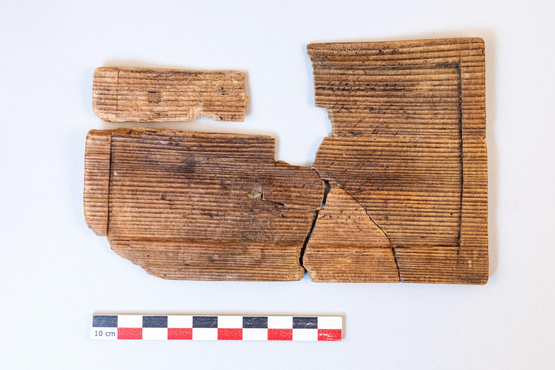 Ink writing tablet, fully hollowed on one side. Six lines of inked handwriting, currently being deciphered by specialists, are still visible. The piece represents the reuse of a former writing tablet, as ink tablets typically do not feature such hollowed surfaces. Credit: Flore Giraud, Inrap