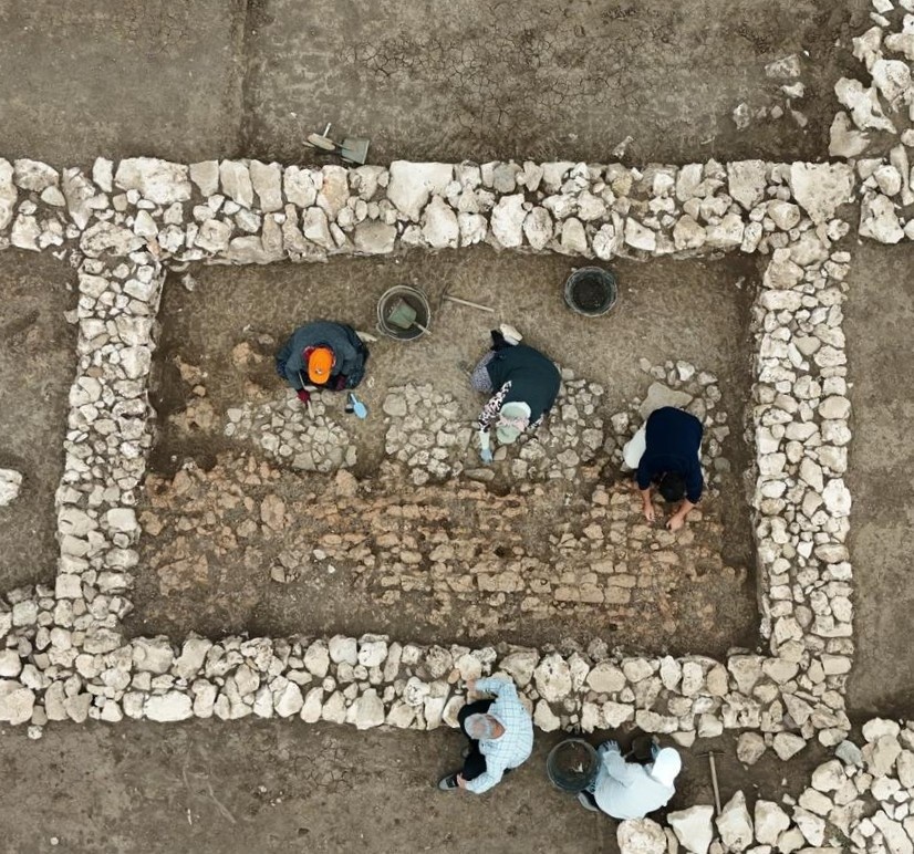 Researchers at Çayönü inspect a fallen mudbrick wall inside a rectangular building, believed to have collapsed during an earthquake some 5,000 years ago. Credit: İHA