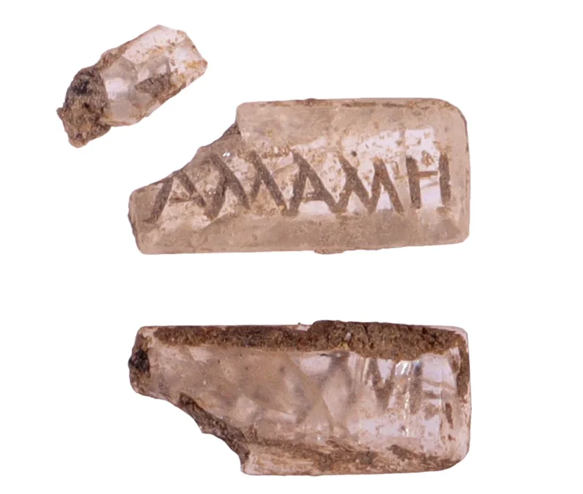 Intaglio (possibly rock crystal) engraved with a Greek name (Allallé?), likely set in a gold ring found nearby. Credit: Frédéric Prodeo, Inrap