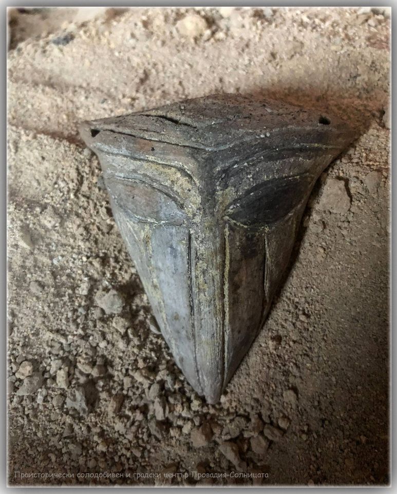 This triangular ceramic head—discovered in earlier excavation seasons at Provadia–Solnitsata—has been interpreted by some researchers as a symbolic representation of a local salt deity. With its stylized ears and eyes but no mouth, the artifact has inspired sensational “alien” claims in some media outlets, though archaeologists stress that it reflects the ritual and artistic traditions of the prehistoric salt-mining community rather than anything extraterrestrial. Credit: Bulgarian National Radio