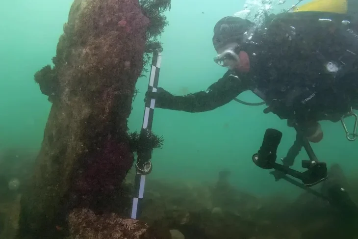 A diver measures the height of an upright granite monolith on the submerged structure; the measuring rod visible in the image is 1 meter long. Photo credit: SAMM, 2023. Study by Yves Fouquet et al., International Journal of Nautical Archaeology (2025).
