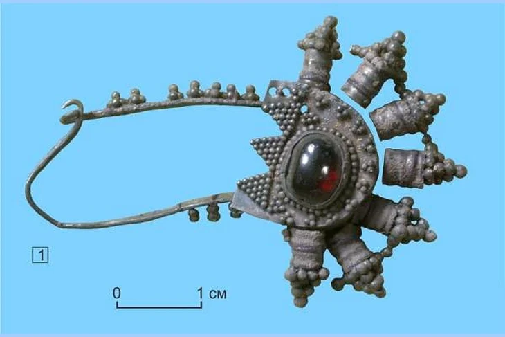 Silver fibula pendant set with a garnet, discovered in an elite early medieval child burial from the Upper Ob region of Siberia. Credit: Novosibirsk State Pedagogical University (NSPU)