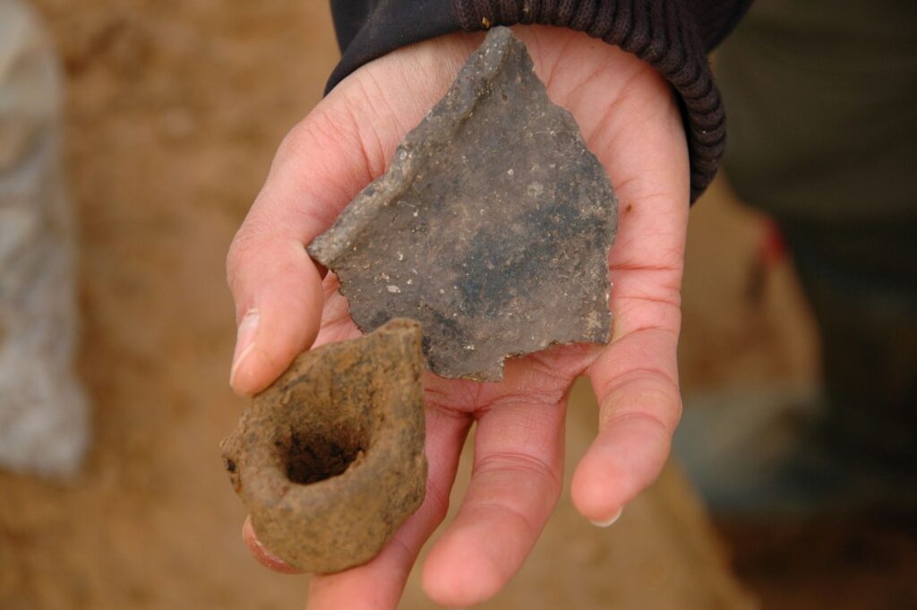 Typical pottery fragments from the early Iron Age: a vessel rim decorated with finger impressions and a sherd featuring a wide rim-mounted handle. Credit: LWL-AfW / S. Düvel