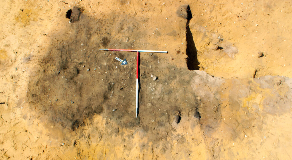  The pyre was a roughly rectangular spread of dark, burnt ground with pieces of cremated bone. Credit: Oxford Cotswold Archaeology