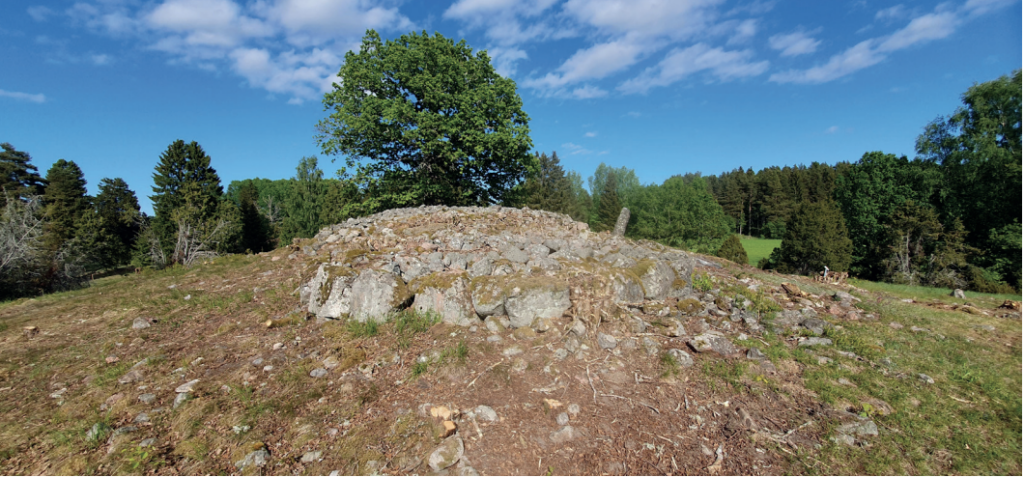 Photo of the cemetery from the south-west. The rectangular stone setting A58 in the foreground, the reconstructed cairn A51 in the centre, and one of the menhirs to the right. Photo: T. Eriksson. Credit: Eriksson et al., 2026