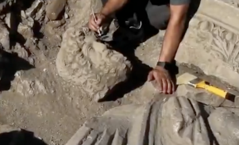 An archaeologist carefully cleans the newly unearthed statue at the excavation site in Aspendos Ancient City,