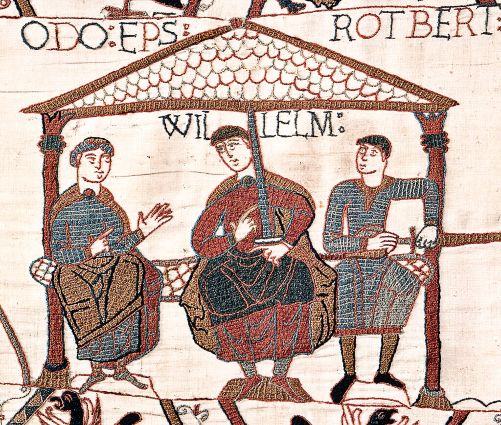 Image from the Bayeux Tapestry showing William with his half-brothers. William is in the centre, Odo is on the left with empty hands, and Robert is on the right with a sword in his hand. Credit: Public Domain
