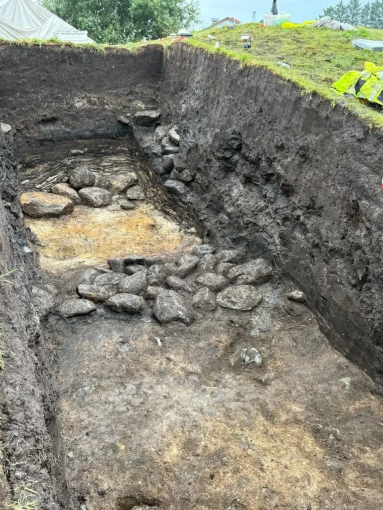 The excavation trench at Grønhaug reveals large stones forming the core of the probable Bronze Age mound, with outer stones marking the kerb around the monument. Credit: Marie Ødegaard/University of Stavanger.