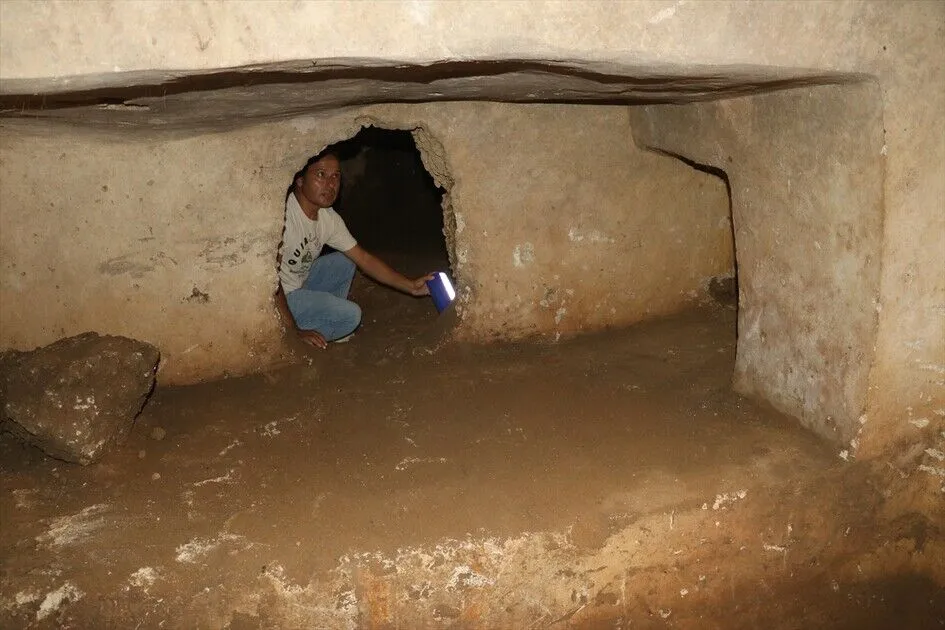Interior of a rock-cut tomb at the necropolis of ancient Aigeai, showing the carved burial platforms along the walls. Credit: AA