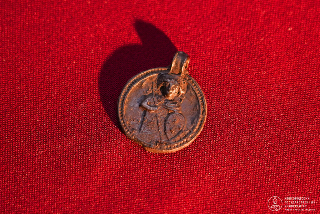 Rare 11th-century serpent amulet discovered in Staraya Russa. One side depicts a Christian warrior saint, possibly Theodore Stratelates, while the reverse carries a snake-haired female image linked to the Medusa tradition. 