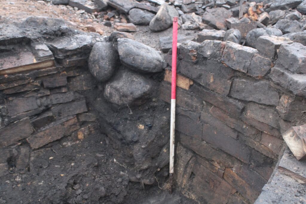  Close-up of the stone-lined structure at Evelix Quarry, showing the carefully built masonry and large boulders packed into the access area. Archaeologists believe the blocking of the entrance may have formed part of the structure’s final phase of use. Credit: Highland Archaeology Services Ltd.