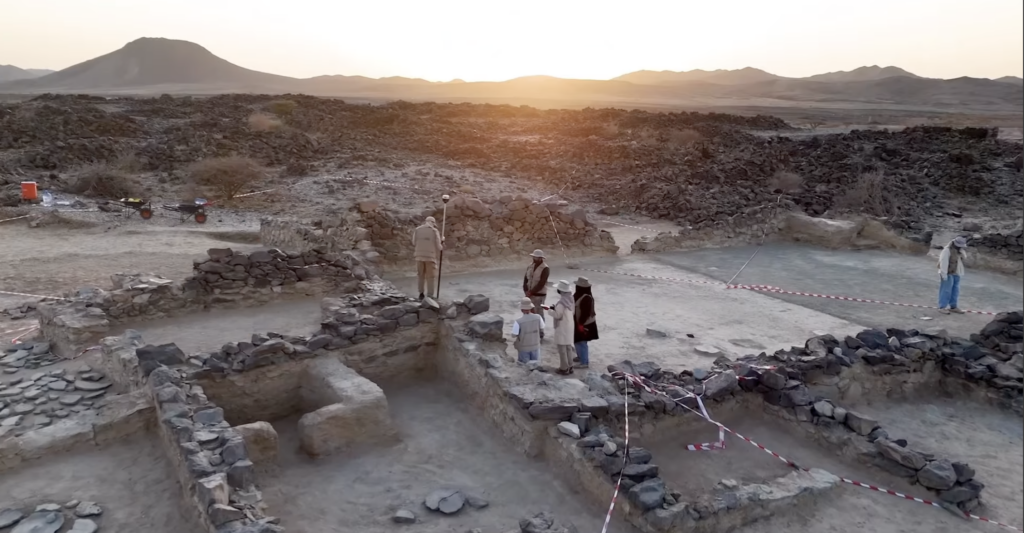 Archaeologists standing among the stone remains of the early Islamic mosque at Al-Ma'mala in Saudi Arabia’s Al-Baha region.