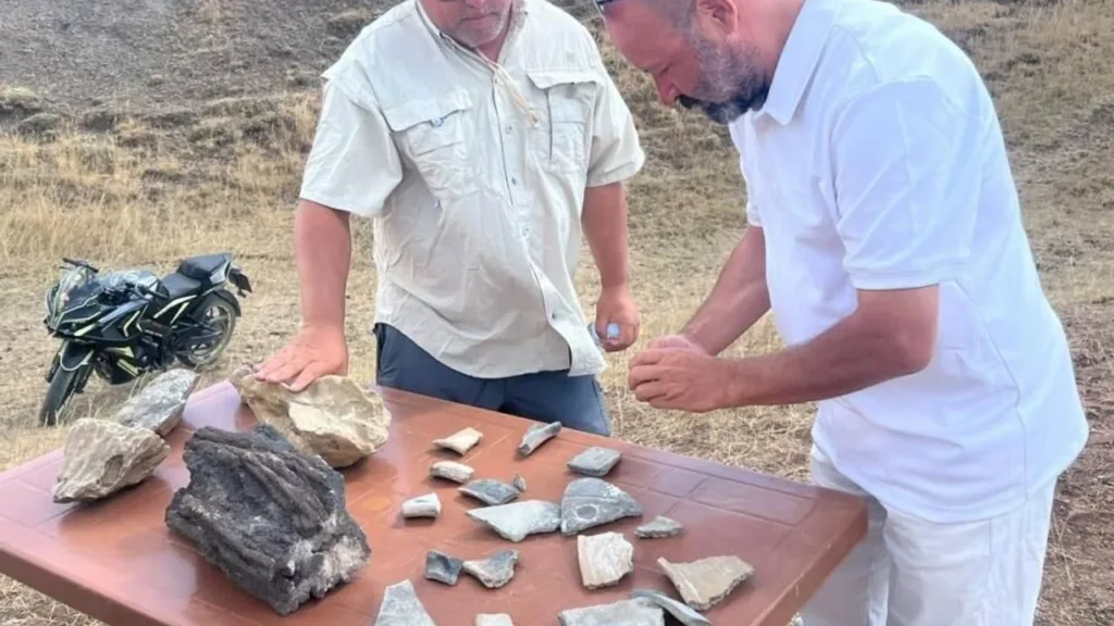 Researchers examining pottery fragments and other finds on a table near Mount Ararat, Türkiye.