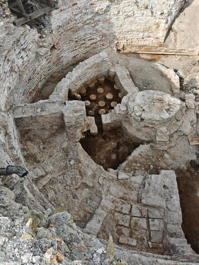 The Roman imperial bath within the south-western tower of the Vrelo–Šarkamen palace, showing the preserved hypocaust pilae and surrounding masonry of the circular bath complex. Photo courtesy of Marija Jović.