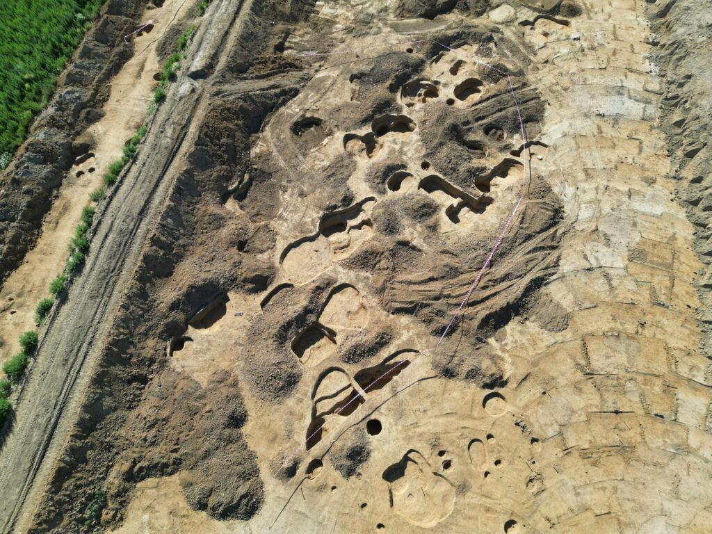 Aerial view of archaeologists excavating prehistoric settlement remains along the D55 highway route in Czechia.