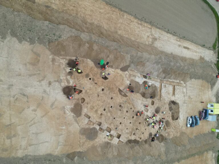 Aerial view of archaeologists excavating prehistoric settlement remains along the D55 highway route in Czechia.