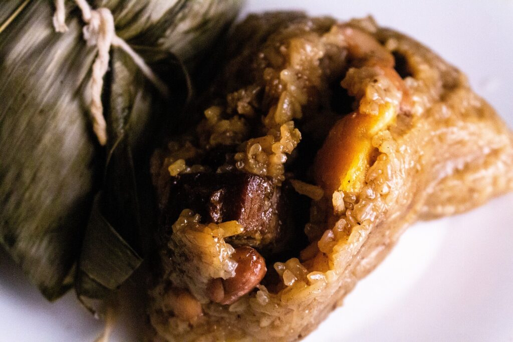 Two Zongzi (Chinese rice dumplings), one wrapped in a bamboo leaf (left) and one unwrapped (right). 