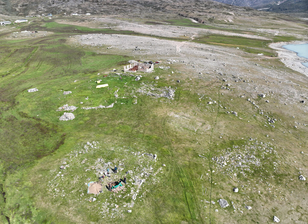 Aerial view of medieval Norse church ruins in Greenland, showing a square cemetery enclosure surrounding the remains of the church.