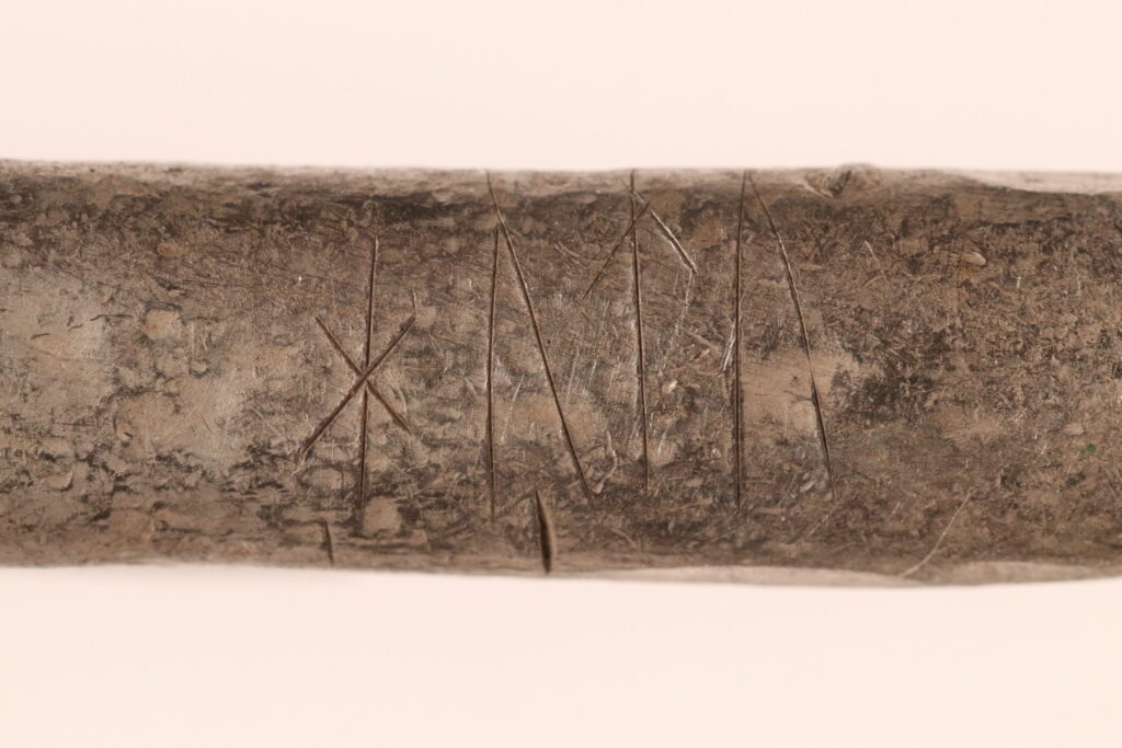Runes are carved into one of the silver ingots from the hoard. The inscription may read “hutu” and could represent a personal name, an ownership mark, or another meaningful designation. Credit: Nordjyske Museer.