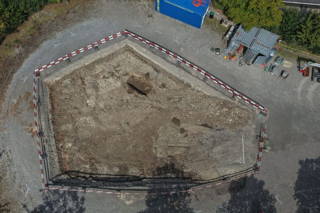 Aerial photograph of the archaeological excavation beside the Roman House at Augusta Raurica, Switzerland, showing the exposed ground and excavation boundaries.