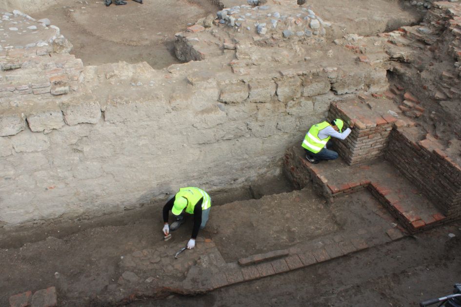 Archaeologists working inside a deep excavation trench surrounded by ancient brick walls in Gabala.