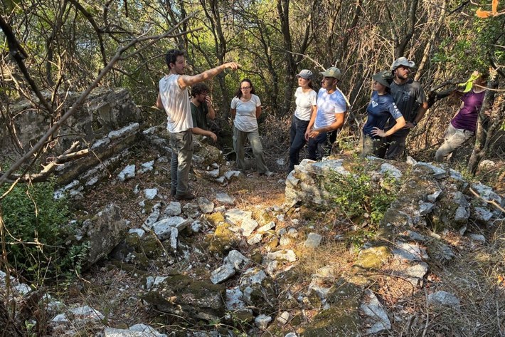 Archaeological researchers examining ancient stone structures in a wooded area at Butrint.