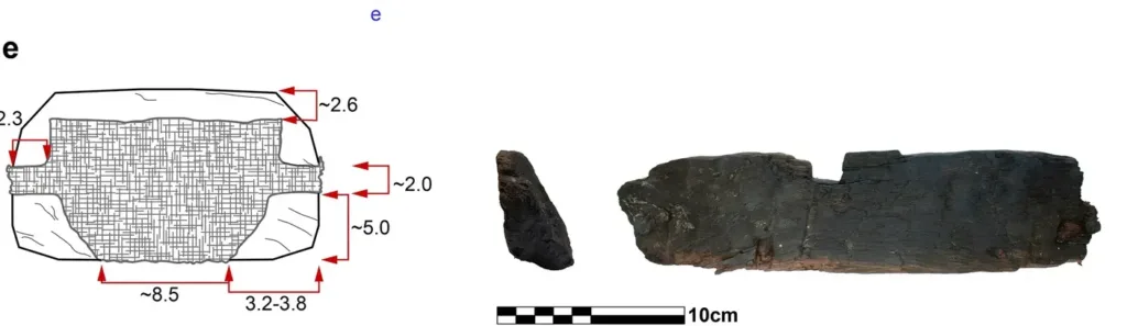 Cross-section of an ancient wooden anchor stock showing a trapezoidal lead weight secured by metal casting bolts on both sides.