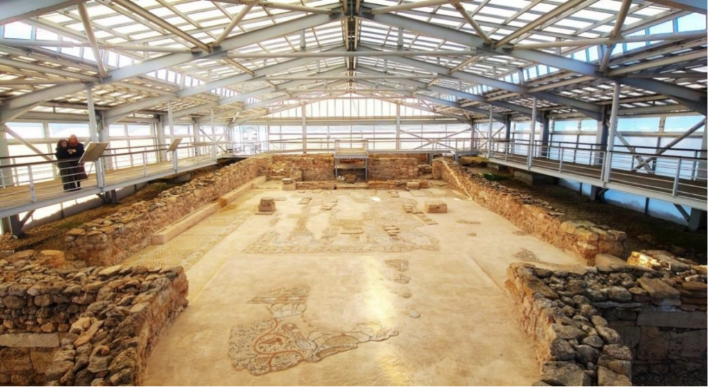 Interior view of the early Byzantine Church of the Four Rivers at Hadrianoupolis, Türkiye, showing ancient stone walls and preserved mosaic floors beneath a protective roof.
