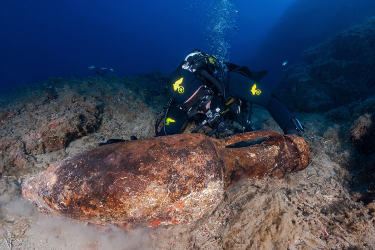 Carabinieri diver examining a large Roman amphora on the seabed near Punta Chiappa, Italy.