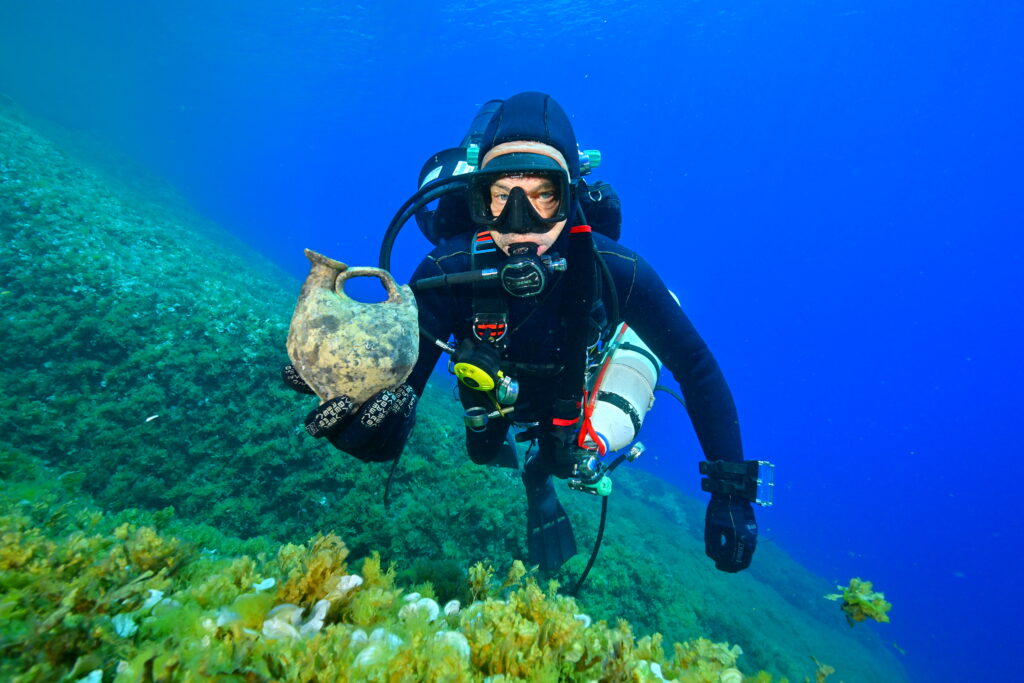 Underwater archaeologist holding an ancient ceramic vessel during investigations of a Hellenistic shipwreck off Croatia.