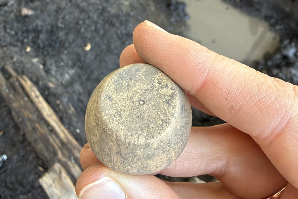 Small, rounded metal weight held between fingers, discovered during archaeological excavations in Tartu, Estonia.