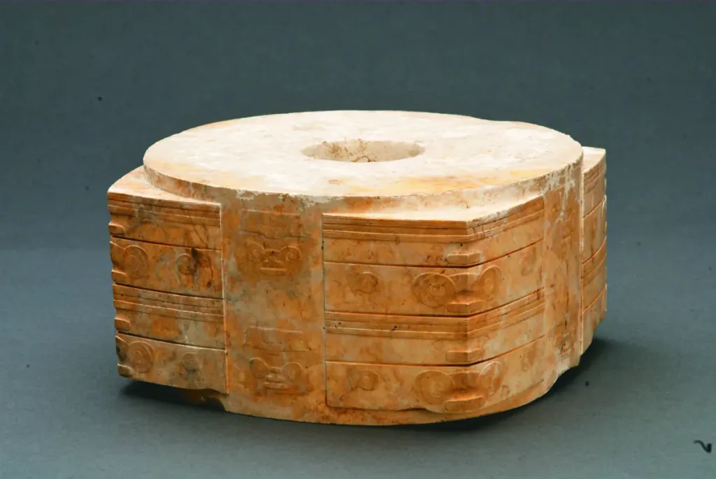 Ancient Liangzhu jade cong with a square outer body, circular central opening, and finely carved decorative motifs.