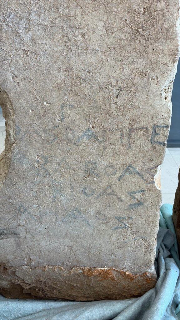 Faint blue and red traces of Messapic writing on an ancient tomb slab.