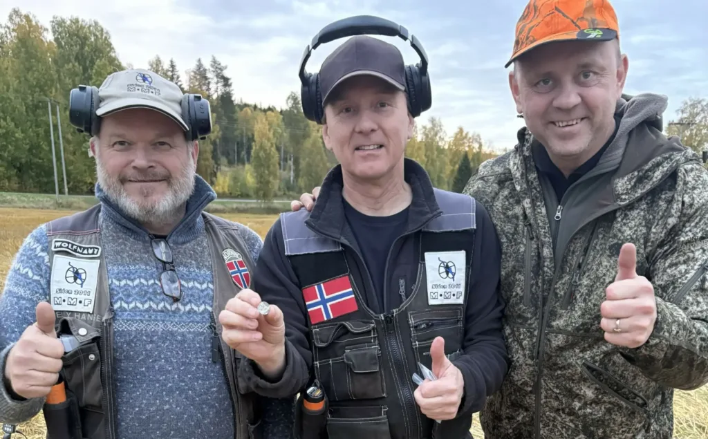 
Metal detectorists Rune Sætre and Vegard Sørlie with landowner Ole Erik Hørstad and coin number 5,000 from the Mørstad Hoard.