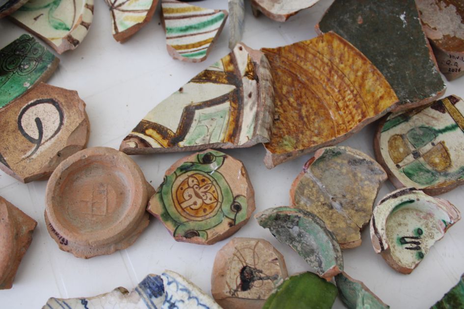 Close-up of medieval glazed pottery fragments with green, yellow, brown, and blue decorative patterns from Gabala.