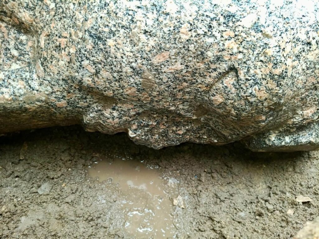 Close-up of the weathered granite surface of an ancient Egyptian royal sculpture uncovered during archaeological excavations.