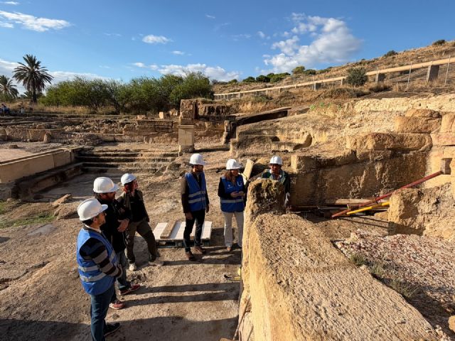 Excavation area at the Roman Baths of Fortuna in Spain, showing ancient stone structures and visitors wearing safety helmets.